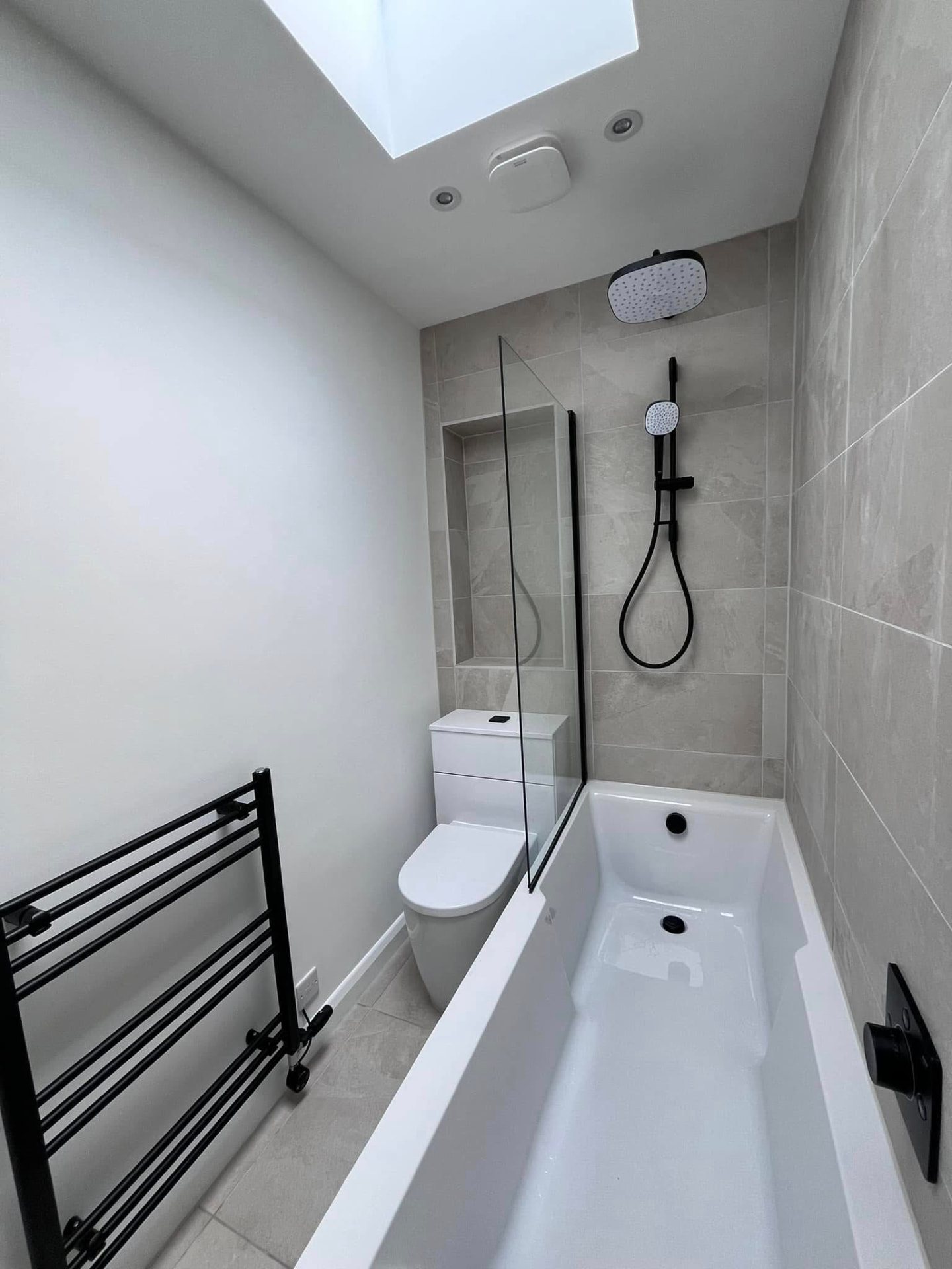 Renovated bathroom with skylight, stone-effect tiling, glass screen and matt black shower