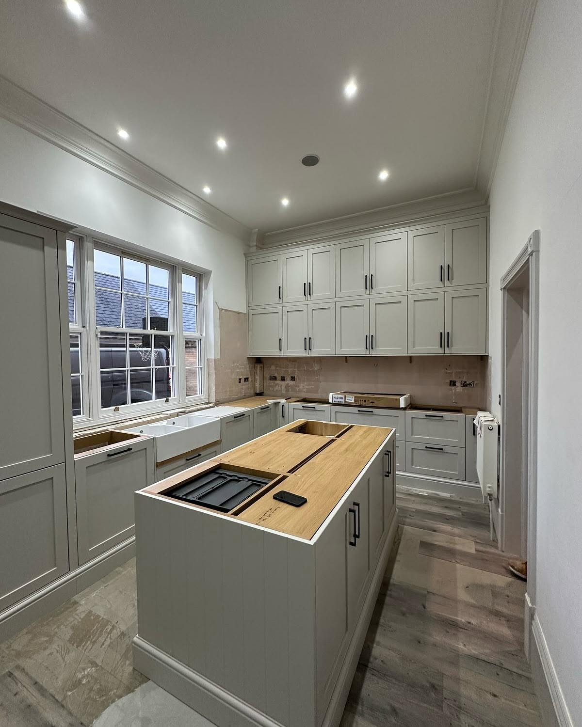 Renovated kitchen with sage in-frame cabinetry, oak-topped island and sash window