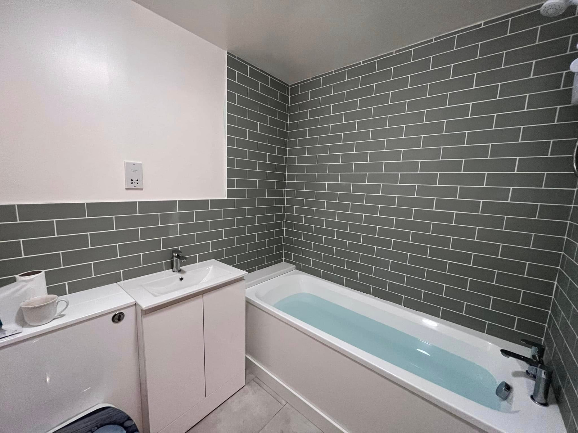 Family bathroom renovation with sage metro tiling, white vanity and bath